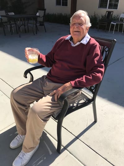 A cheerful resident enjoying a drink in an outdoor space