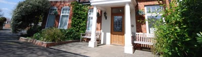Front entrance of The Grange Care Home with lush greenery.