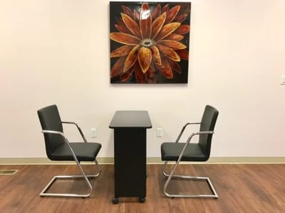 Chairs and table with a floral painting in the background.