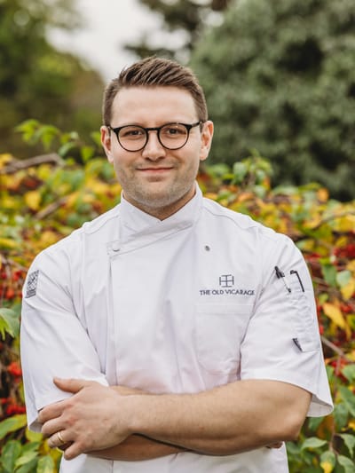 Chef in a white uniform outdoors, smiling