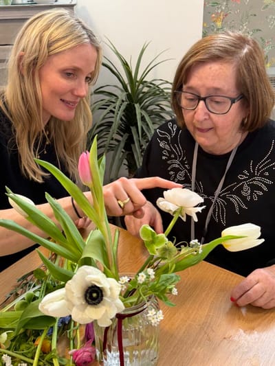 Resident and staff engaging in flower arranging activity.