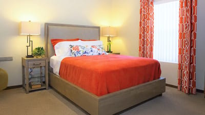 A well-decorated bedroom with a red bed cover