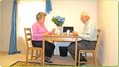 Two seniors engaged at a table with flowers.