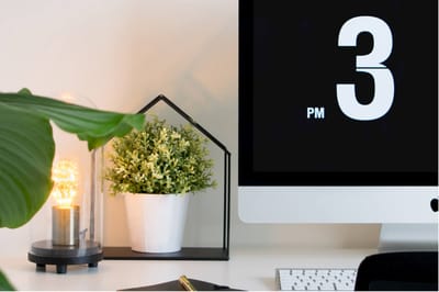 A modern desk setup with plants and a clock.