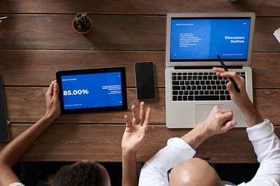 Two people working with devices on a table