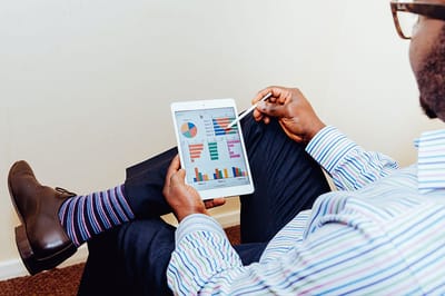 Man using a tablet with charts and graphs.