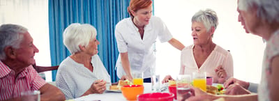 Residents enjoying a meal together with staff assistance