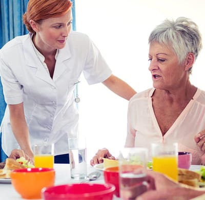 A staff member serving food to a resident during mealtime