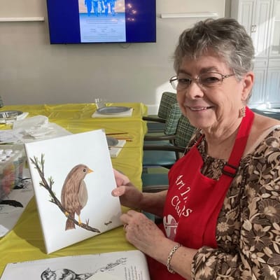 Resident showing a finished painting in an art activity