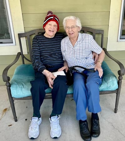 Two residents enjoying time together on a bench