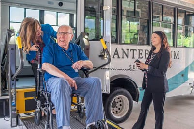 Resident being assisted onto a facility shuttle by staff