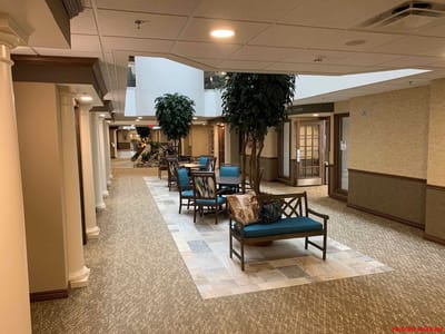 Spacious lobby with seating and greenery at Virginia Greens Retirement Community.