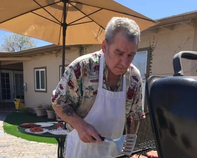 Resident barbecuing outdoors in a sunny courtyard