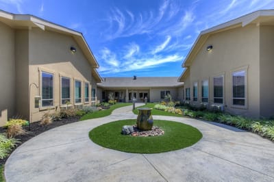 Exterior view of an assisted living facility entrance with landscaped pathway