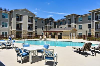 Outdoor pool area with lounge chairs and apartments