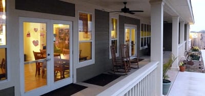 Outdoor seating area with rocking chairs and dining space visible