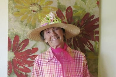 Resident smiling in a colorful outfit with a floral background