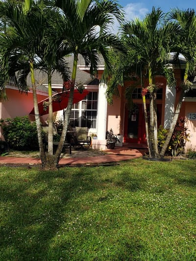 Front entrance of a senior living facility surrounded by palm trees