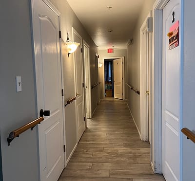 Well-lit hallway with resident doors and handrails