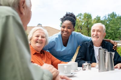 Residents with a staff member outdoors enjoying conversation