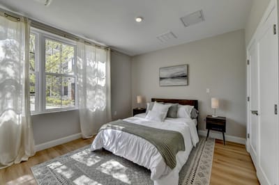 Brightly lit private resident room with a bed and artwork