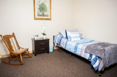 A cozy resident room with a bed and chair