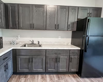 Modern kitchen area with dark cabinets and appliances