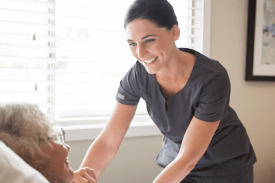 A caregiver smiling while attending to a resident in bed