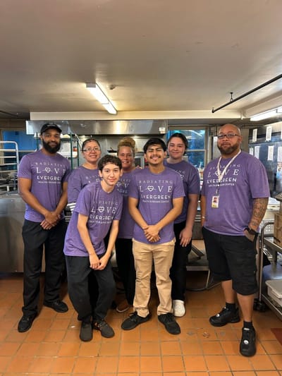 Staff members in a kitchen setting wearing Evergreen shirts