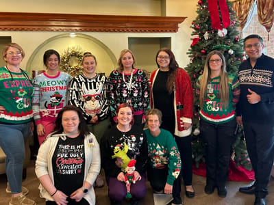 Staff and residents wearing festive holiday sweaters