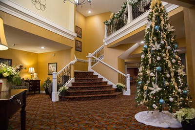 Interior view of a decorated lobby with a staircase and Christmas tree