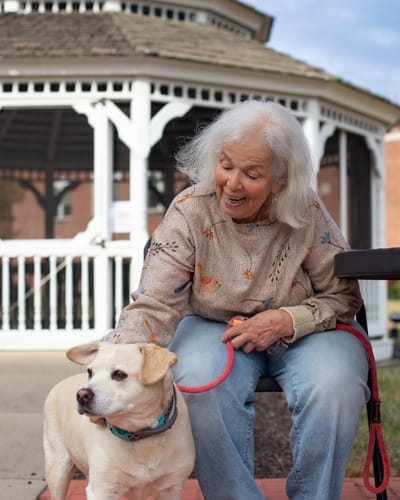 Elderly woman petting a dog near a gazebo