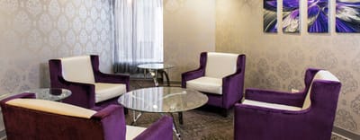 Bright, modern common area with purple chairs and glass tables