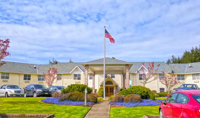 Exterior view of Lakeview Senior Living with flowers and flag