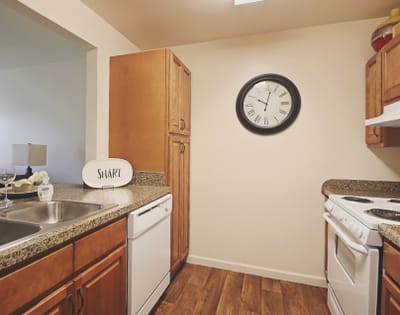 A kitchen area in a resident unit with clock and cabinets
