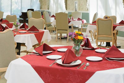 Well-set dining room with red tablecloths and flowers