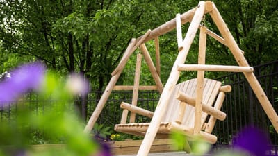Outdoor wooden swing in a landscaped area