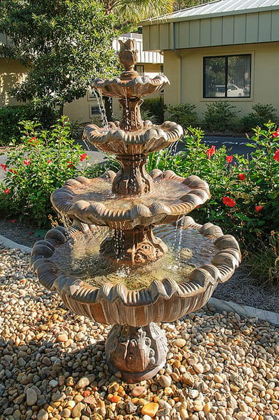 A decorative outdoor fountain surrounded by greenery