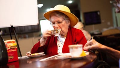 Resident enjoying tea at a communal table