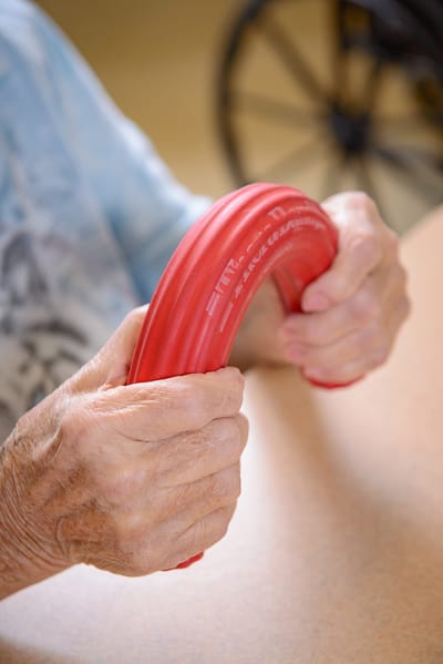 Elderly hands holding a red exercise device