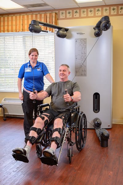 Resident using therapy equipment with staff assistance