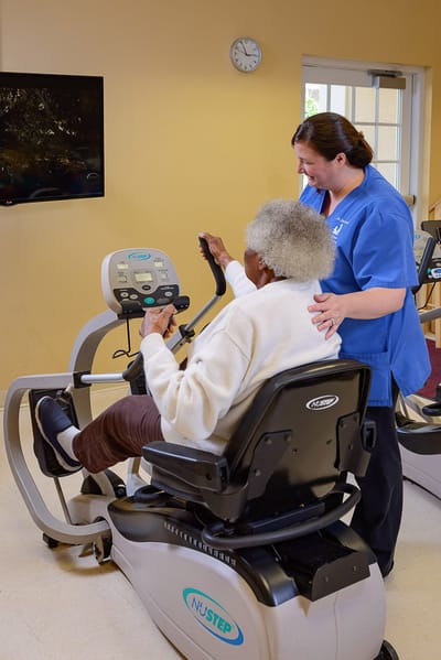 Staff assisting a resident with exercise equipment