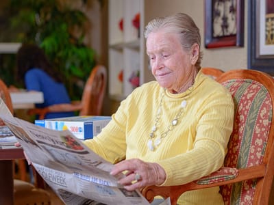 Resident reading a newspaper in a common area