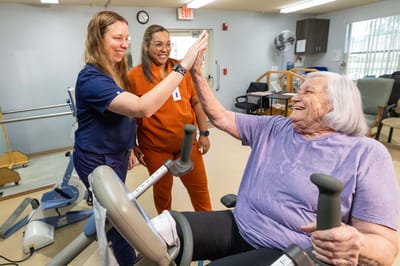 Staff assisting a resident with exercise equipment