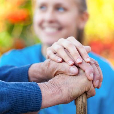 Hands of a caregiver and a resident resting together