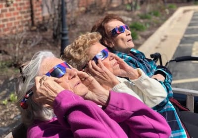 Three seniors watching a solar eclipse with special glasses