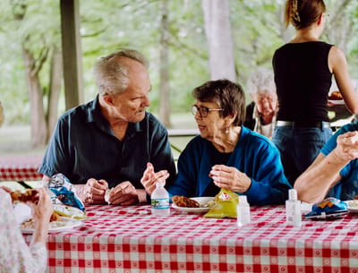 Residents enjoying a meal outdoors at a picnic table