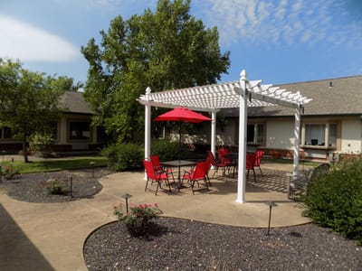 Outdoor seating area with red chairs under a pergola