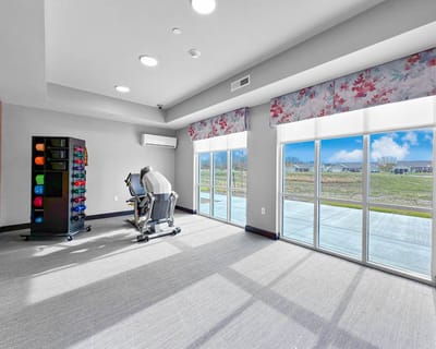Bright fitness room with equipment and large windows