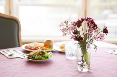 A dining table set with meals and flowers